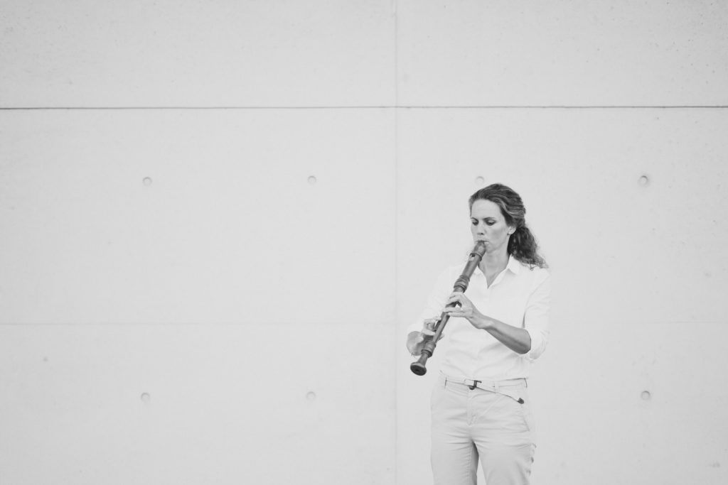 Charlotte Schmidt-Berger spielt Blockflöte vor grauer Wand