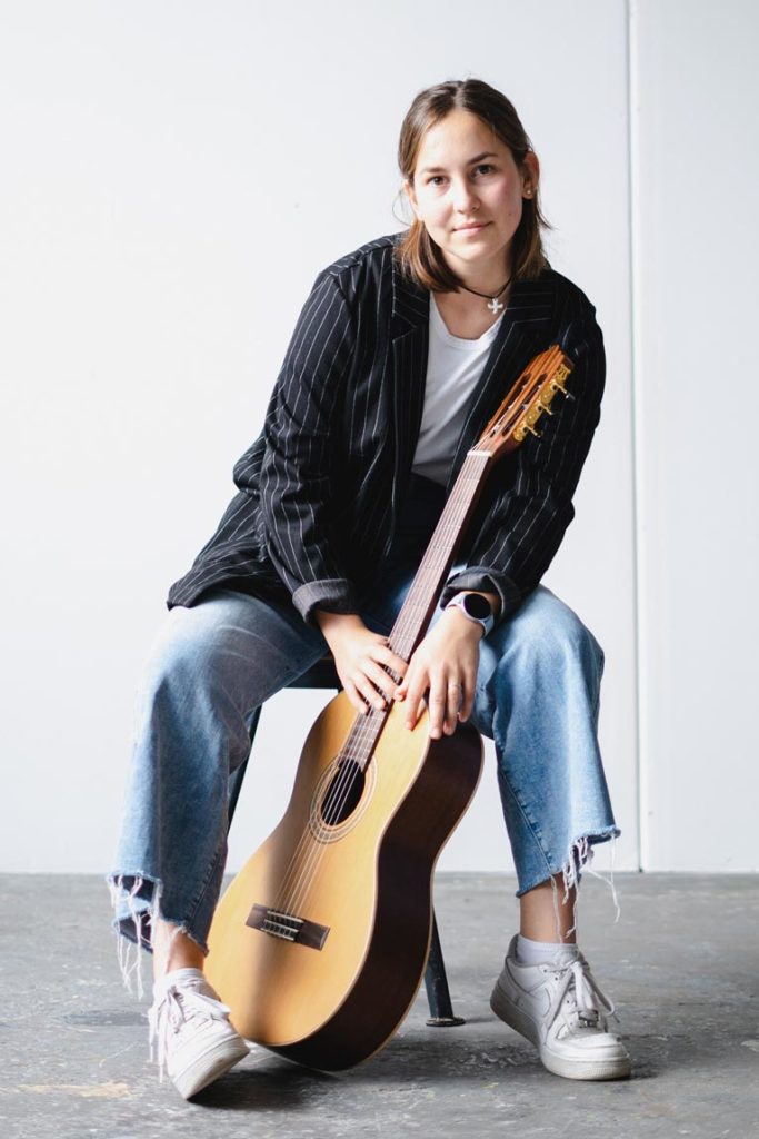 Musikerportrait Tina Wirsching mit Gitarre auf Hocker